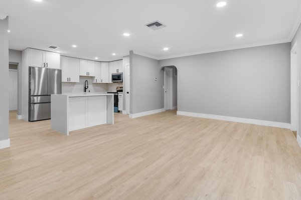 This beautifully renovated open-concept home features a modern kitchen with stainless steel appliances, sleek white cabinetry, and a spacious living area perfect for entertaining.